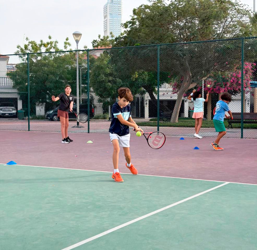 Junior tennis lesson with coach on outdoor court
