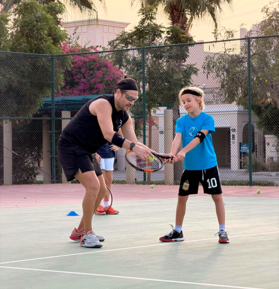Children training with tennis rackets on court