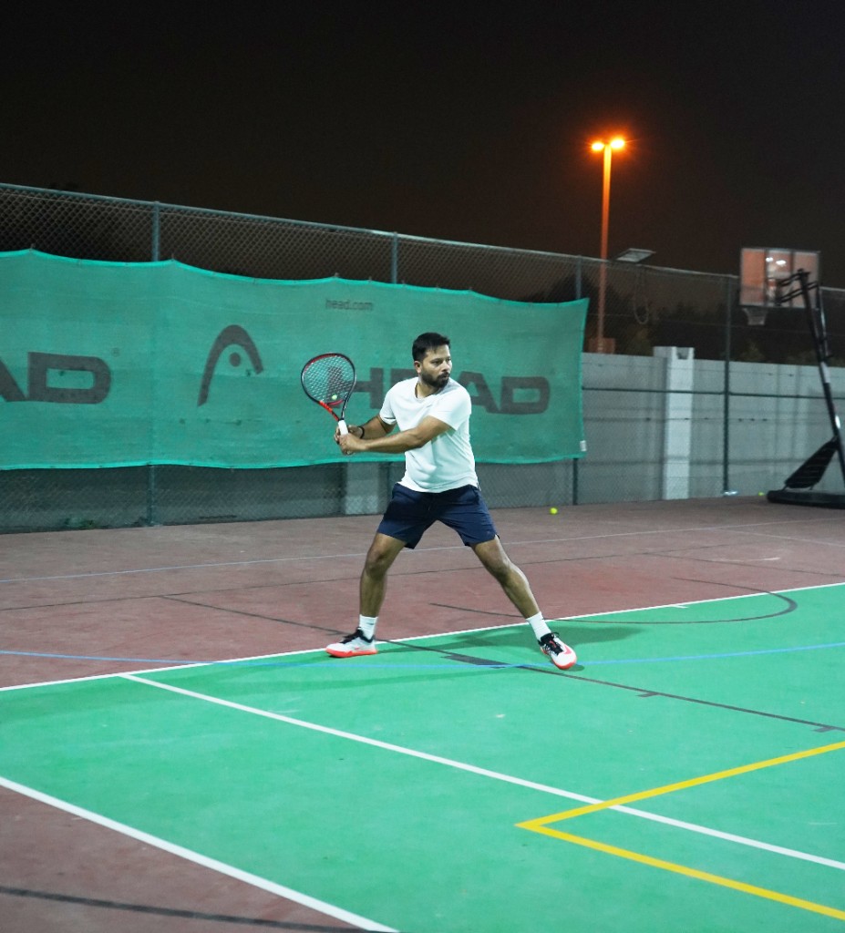 Tennis player serving under court lights at night